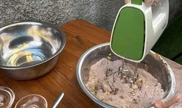 Adonan di mangkuk besar dengan mixer hijau.