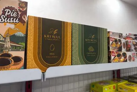 Kotak KriWul dipajang di rak toko oleh-oleh di antara produk lain.