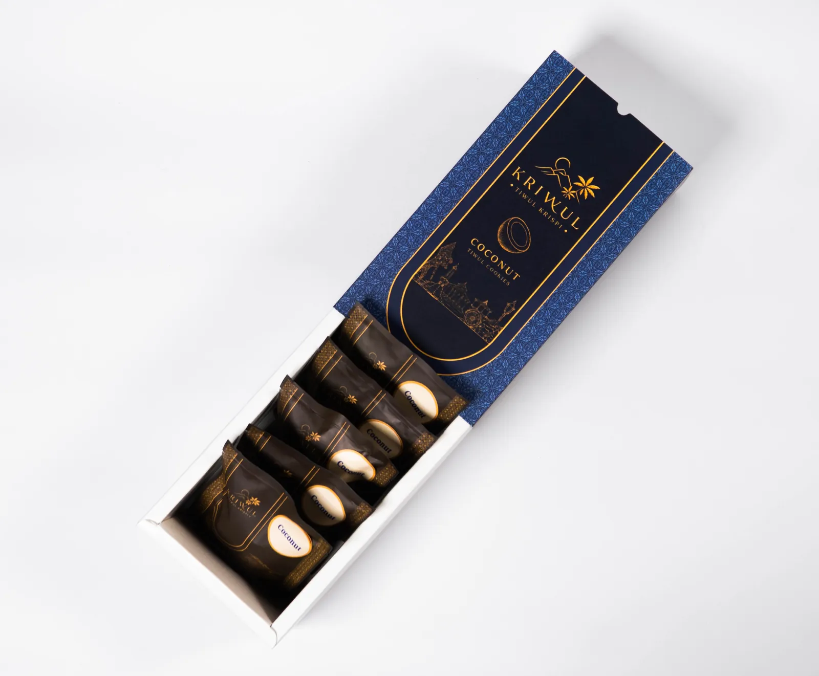 Kotak KriWul Coconut biru tua terbuka, baki putih berisi lima pouch cokelat tua berlabel krem.